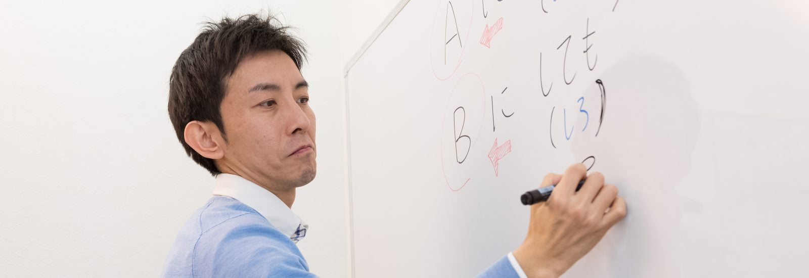 Japanese teacher writing Japanese on whiteboard
